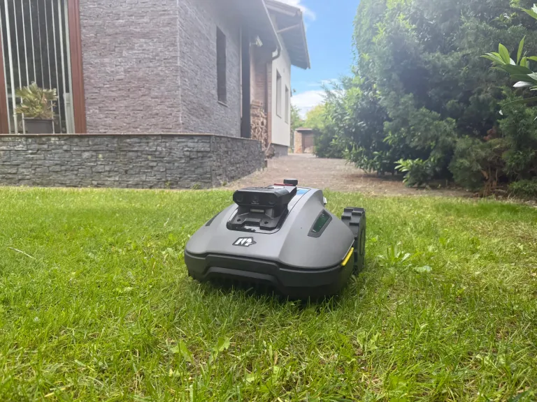 Robotfűnyíró a pázsiton téglaház előtt