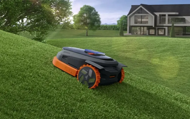 Narancs-fekete Segway Navimow robotfűnyíró lejtős gyepen, háttérben modern családi ház